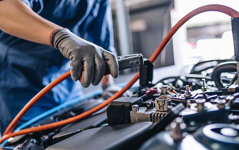 A man wearing blue gloves is repairing a car engine, focused on his work.