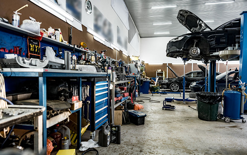 A car repair shop featuring a vehicle on the floor, surrounded by tools and equipment for automotive maintenance.